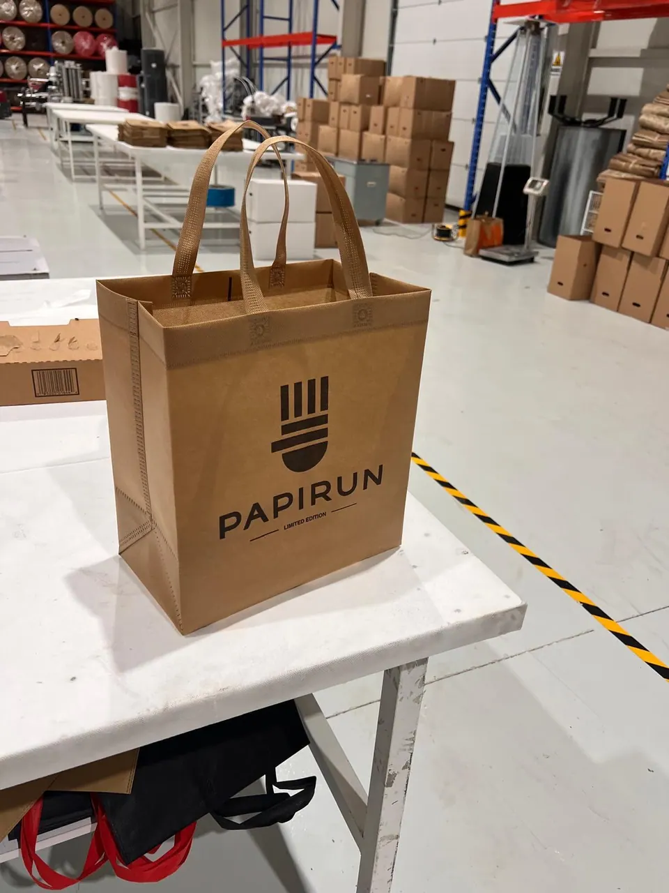 Branded box bag showing its handles and side gusset inside the Kobags factory