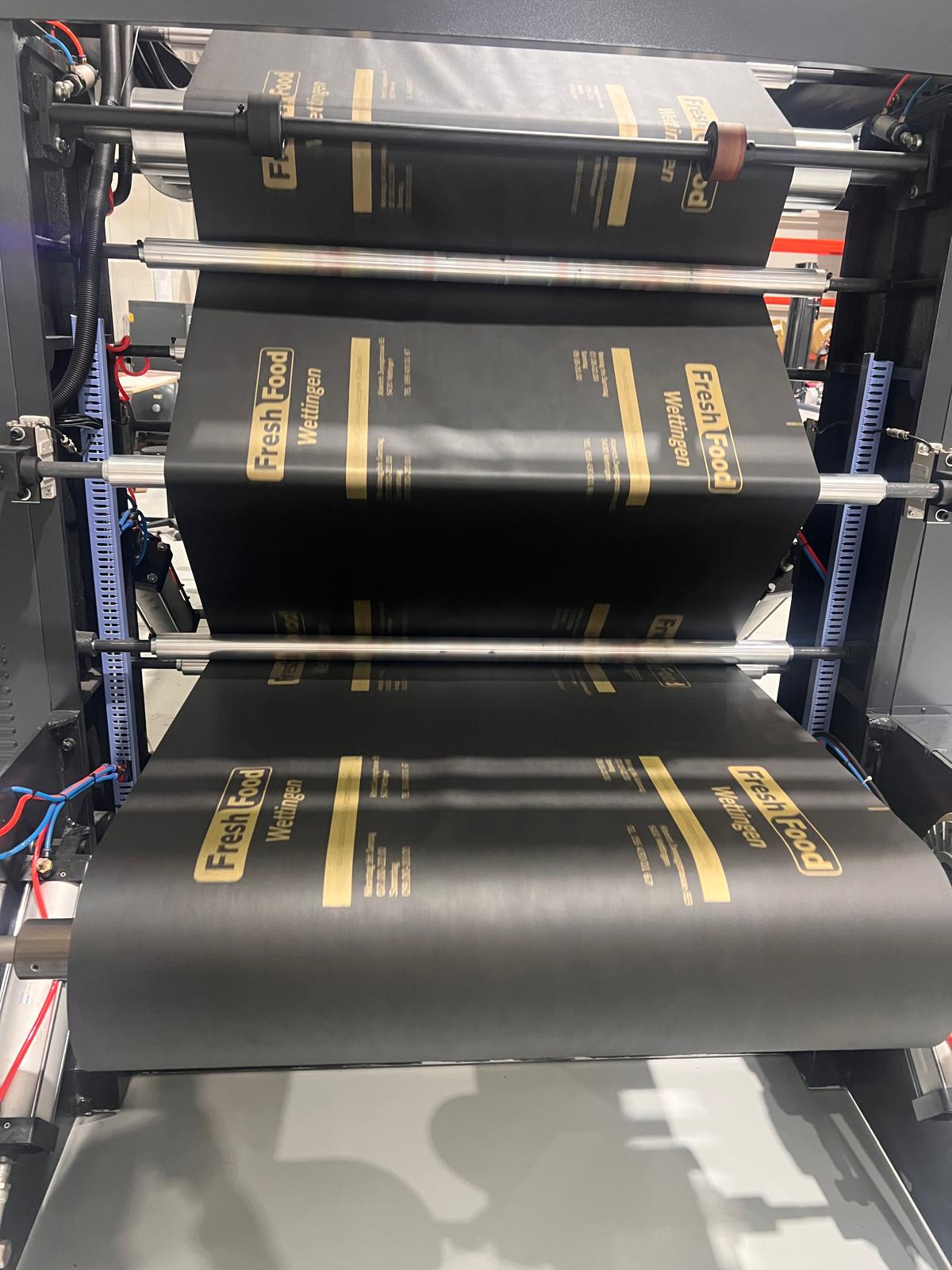 Black bag material with gold printing passing through the Kobags production rollers